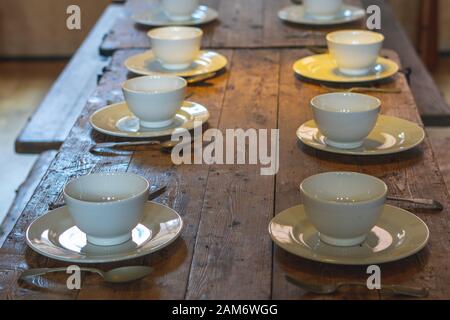 plates bowls and cutlery on a wooden table ready for food to be served Stock Photo
