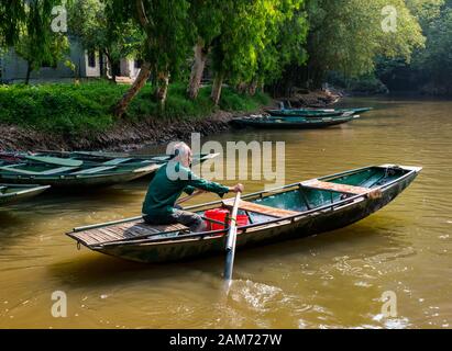 Older local Asian man with grey beard rowing sampan, Tam Coc, Ninh Binh, Vietnam, Asia