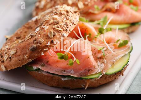 Two bagel sandwiches with sliced salt salmon, cream cheese, cucumber, and micro greens closeup Stock Photo