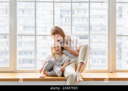 Happy mother hugs her cute girl while having fun together Stock Photo