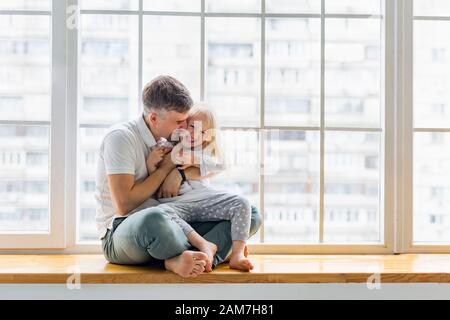 Happy father hugs her cute girl while having fun together Stock Photo
