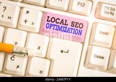 Word writing text Local Seo Optimization. Business photo showcasing increase Search Visibility to Rank on Top list White pc keyboard with empty note p Stock Photo