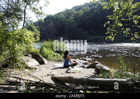Woman doing yoga on side of river Stock Photo
