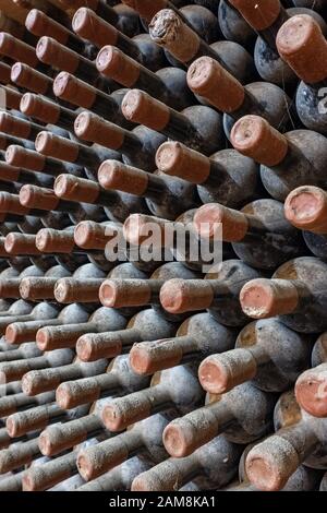 Wine bottles stacked up in old wine cellar close-up background Stock Photo