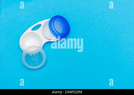 Contact lens case open on a bright blue flat lay background. Vision, healthcare, eye sight concepts. Stock Photo