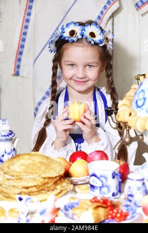 Little girl is holding an apple. Maslenitsa Stock Photo