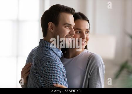 Happy young couple hug look in distance dreaming Stock Photo