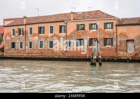rising damp effects on plaster facade of traditional houses on canal, shot in bright fall light at Murano, Venice, Veneto, Italy Stock Photo