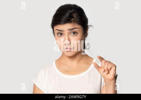 Upset millennial indian ethnicity girl showing small size. Stock Photo
