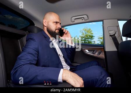 Successful young man talking on the phone in a car. Stock Photo