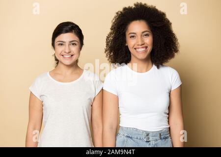Two happy diverse multiracial millennial ladies standing side by side. Stock Photo