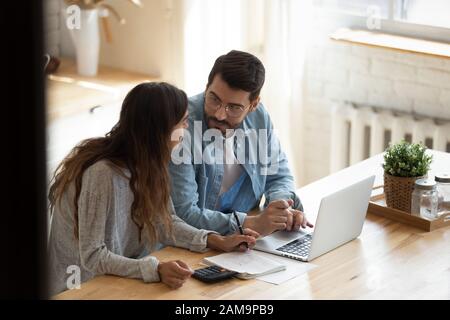 Focused family couple discussing monthly expenses, using computer banking applications. Stock Photo