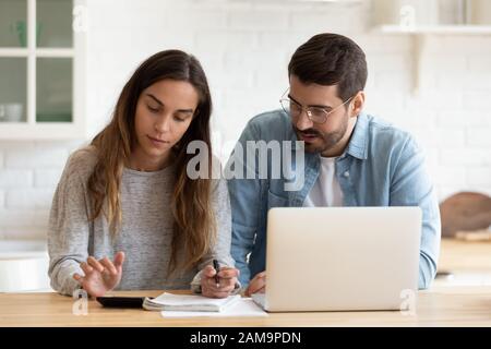 Concentrated young married spouse calculating monthly family budget together. Stock Photo