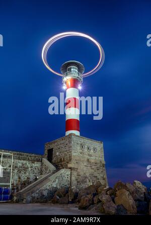 long exposure photography of lights forming shapes behind a lighthouse representing the drone lights.Port Burgas bulgaria. Stock Photo