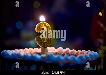 Burning candle on a cake in the dark. Stock Photo