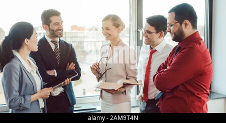 Business people standing by the window discussing a project Stock Photo