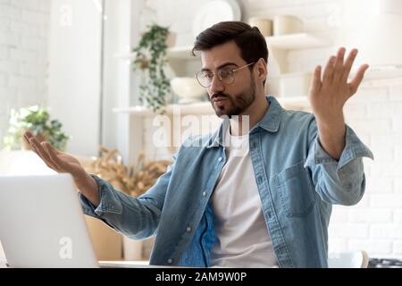 Head shot young caucasian man irritated by broken computer. Stock Photo