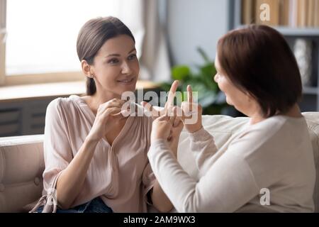 Deaf-mute adult mom and daughter talk using sign language Stock Photo