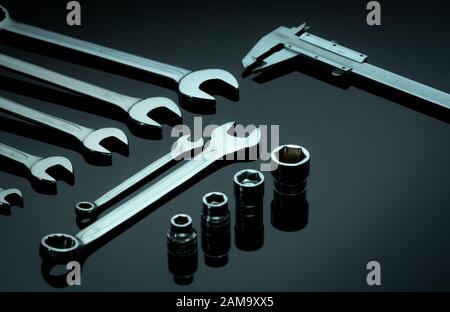 Set of chrome wrenches or spanners, hexagon socket, and vernier caliper on dark table in workshop. Chrome vanadium spanner wrench. Silver wrenches. Stock Photo