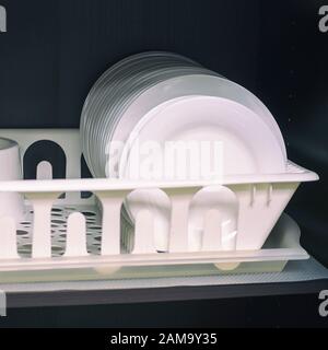 Clean white ceramic plates on a shelf in a cupboard. Selective focus Stock Photo