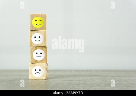 Conceptual the customer responded to the survey. A wooden cube with face symbol on wooden table. Depicts that customer is very satisfied. Service expe Stock Photo