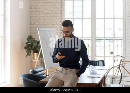 Arabian businessman busy using modern smartphone in office Stock Photo
