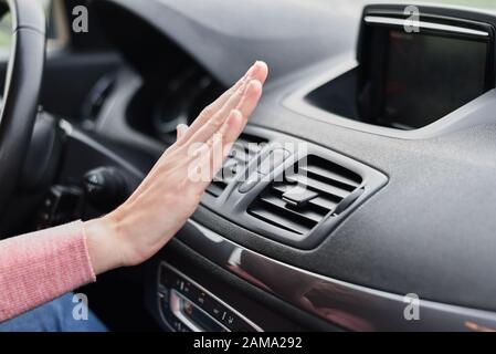 Woman hand on air conditioner ventilation grille in car. Climate control panel Stock Photo