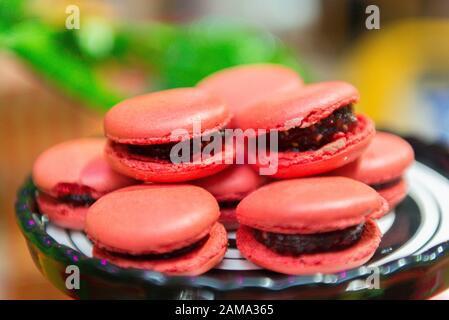 Red Macaroons. Several strawberries-flavored pink macaroons on a white and black ceramic tray. Children's party decoration with the detective theme. S Stock Photo