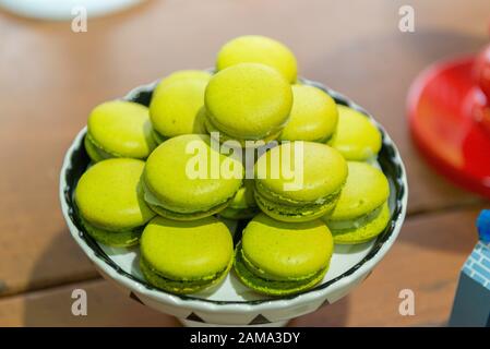 Lemon Macaroons. Several lemon-flavored green macaroons on a white and black ceramic tray. Children's party decoration with the detective theme. Selec Stock Photo