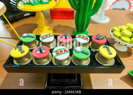 Custom cupcakes with magnifying glass fondant icing, binoculars, footprints and other conceptual research shapes on a black tray. Children's party cak Stock Photo