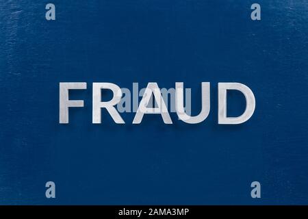 the word fraud laid with silver metal letters on classic blue painted board surface, Stock Photo