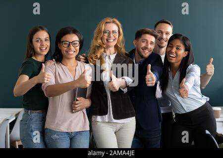 Interns and aged ceo looking at camera showing thumbs up Stock Photo