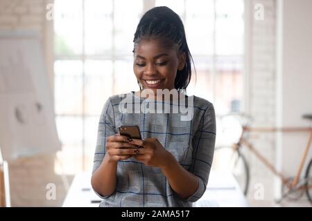 Smiling biracial female employee using modern cellphone Stock Photo