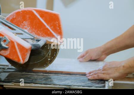 Worker use wet sawing machine for tile cutting equipment on the construction tile floor Stock Photo