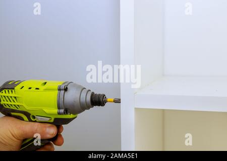 Furniture assembling interior of white plastic clothing with shelves a screwdriver handle Stock Photo