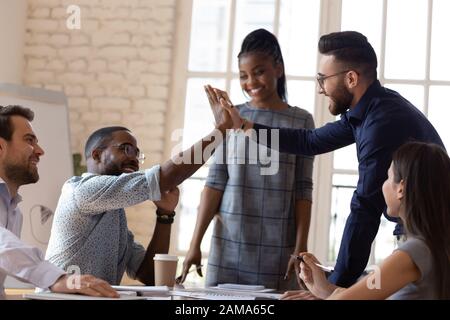 Excited diverse male employees give high five at briefing Stock Photo
