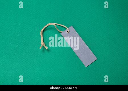 cardboard label with a string. without inscriptions. on a green background. place for text Stock Photo