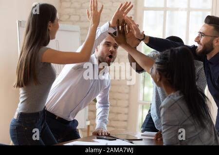 Overjoyed diverse employees give high five celebrating success Stock Photo