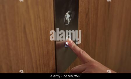woman hand presses elevator button to go down to ground floor of modern building extreme close view Stock Photo