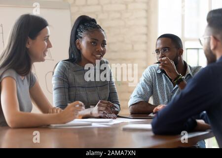 Multiethnic employees talk discussing ideas at meeting Stock Photo