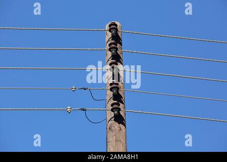 Electric wooden pole with wires / cables close up against blue sky Stock Photo