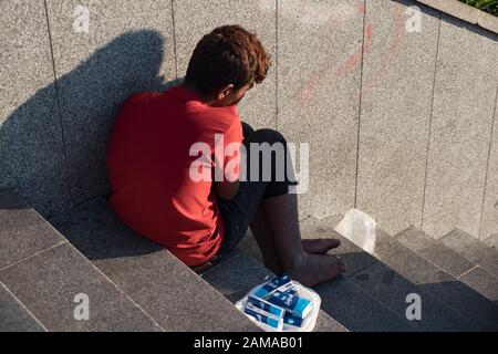 ISTANBUL, TURKEY - JULY 30 2019: Beggar teenager without shoes on the stairs. Stock Photo