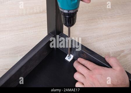 Power electric screwdriver. Carpenter working with hand tool on work bench. Closeup view. Stock Photo