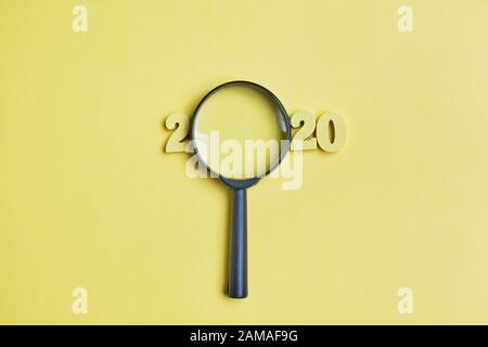 Abstract 2020 of wooden figures and magnifying glass. Top view. Close up. Stock Photo