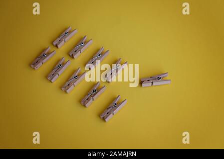 Many wooden clothespins lie on a yellow background. Stock Photo