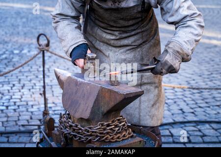 Blacksmith working metal with hammer on the anvil in the forge Stock Photo