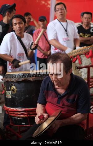 A senior man plays a traditional cymbal in front of young drum players in Chinese new year celebration festival. Stock Photo