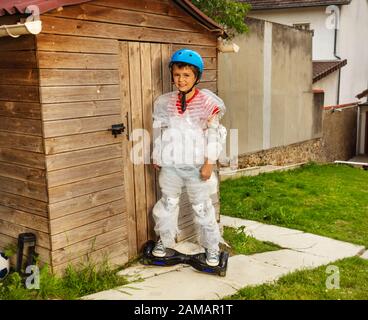 Boy ride a gyro scooter wrapped in overprotective bubble wrap and wearing helmet in the garden Stock Photo