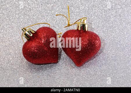 two large red glitter hearts on glittering silver glitter background Stock Photo