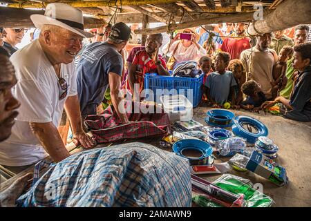 Locals and tourists meet on a beach in Papua New Guinea. Fishing accessories are a perfect gift for guests. Fair distribution is placed in the hands of the village chief in front of everyone Stock Photo